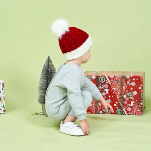 Detail of red and white knit Christmas hat with soft white pompom for kids