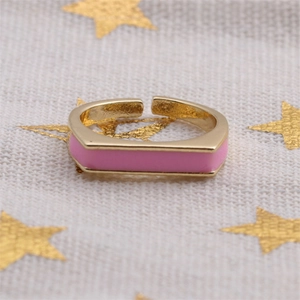 Detailed close-up of a gold-plated open ring with a pink enamel rectangular inlay