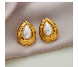 Close-up of teardrop pearl earrings with gold rippled metal edges on silk background