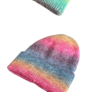 Close-up of thick knit texture and rainbow tie-dye gradient on warm winter beanie