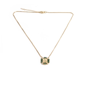 Detail of golden necklace with square emerald green gemstone and sparkling zircons