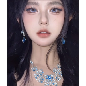 Close-up of elegant flower leaf necklace and earrings set with blue crystal accents