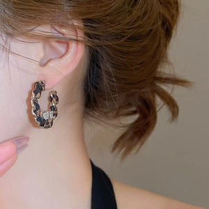 Détail d'une boucle d'oreille C en tissu léopard, chaîne dorée et cristal carré