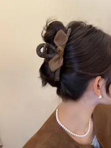 Dettaglio di un'elegante pinza per capelli con fiocco in pelle marrone su un modello