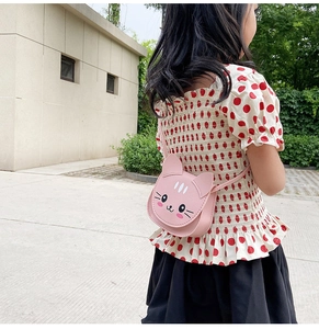 Pink cat-shaped leather crossbody bag for kids shown being worn in an outdoor setting