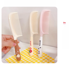 Detail view of cute cartoon hairbrushes in pink and beige with strawberry and panda motifs