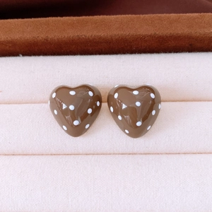 Detail view of brown heart-shaped earrings with white polka dots on a fabric jewelry tray