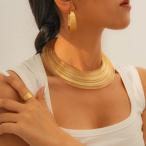 Detail eines geschichteten Gold-Chokers mit passenden Reifen und Ring am Modell
