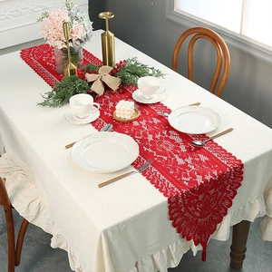 Macro shot of red lace table runner with intricate hollow floral patterns and tassels