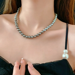 Close-up of elegant dark grey metallic pearl necklace on model's neck for a French style