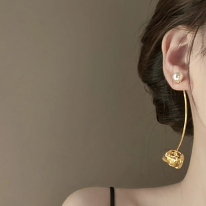 Detail of minimalist floral pearl drop earrings with elegant gold curved stem design