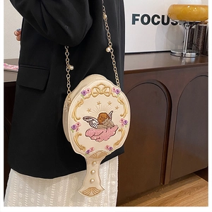 Detail of angel embroidery and gold pearl chain on a white mirror-shaped crossbody bag