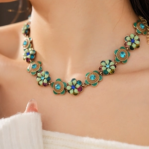Detail of vintage flower necklace featuring green enamel petals and colorful rhinestones