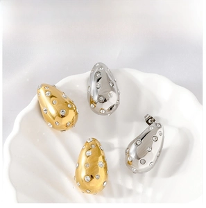 Macro view of gold and silver teardrop stud earrings with cubic zirconia on shell dish