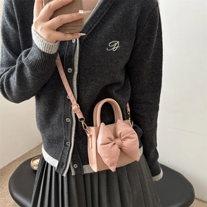 Pink mini crossbody bag with a cute bow detail, shown on a model for spring fashion style