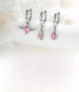 Detailed macro view of silver hoop earrings with pink zircon heart and fishbone charms