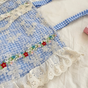 Detail of floral embroidery on blue checkered canvas with delicate white lace trim