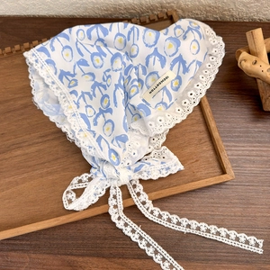 Close-up of blue floral cotton headscarf with white lace trim and 100% cotton label