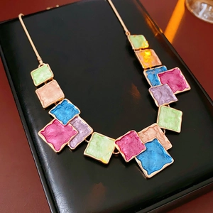 Detailed macro view of colorful square enamel charms on a gold-plated statement necklace
