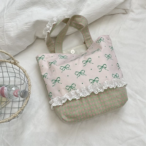 Detailed view of canvas tote bag featuring delicate lace trim and magnetic metal closure