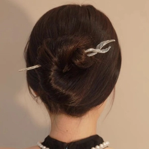 Silver leaf-shaped hair pin detail showing metallic texture in a dark hair bun