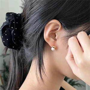 Close-up of minimalist gold pearl stud earring worn by model for elegant style