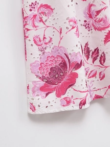 Détail du tissu blanc brodé avec imprimé floral rose et finitions ajourées élégantes
