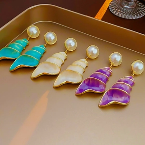 Detailed view of vintage conch shell earrings with pearl studs in three vibrant colors