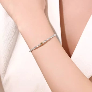 Detail of twisted silver chain with a polished gold bead on a woman's wrist