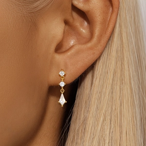 Détail macro de boucles d'oreilles pendantes dorées avec zircons en forme de cerf-volant