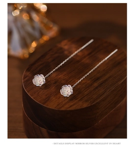 Close-up of silver rose tassel earrings on wooden gift box with elegant bokeh light