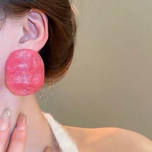 Close-up of pink oversized round earrings with textured resin finish on model
