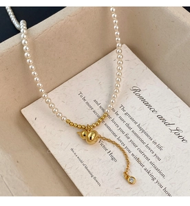 Vue macro du collier avec pendentif gourde dorée et perles blanches sur fond de carte
