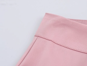 Vue détaillée de la texture du tissu rose et des coutures précises sur la taille du costume