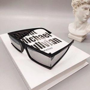 Futuristic square sunglasses with silver mirrored lenses on minimalist white book decor