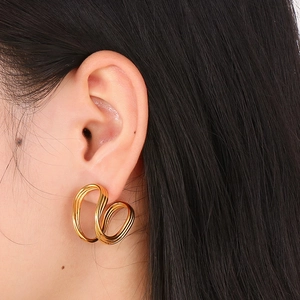 Detailed view of twisted gold geometric C-shaped earrings on a female model
