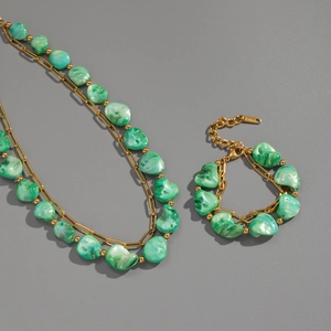 Macro shot of gold stainless steel necklace set with irregular green stone beads