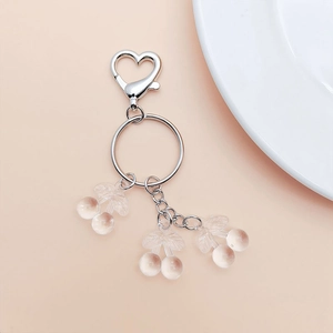 Close-up of cute transparent pink cherry charms with silver heart-shaped keyring