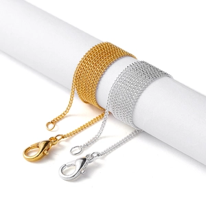 Close-up of gold and silver extension chains with lobster clasps on a white cylinder