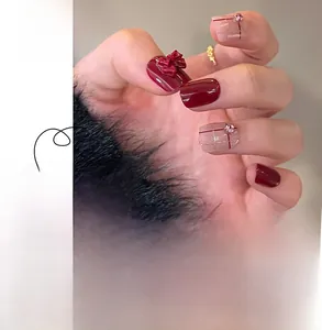 Detail of red and pink checkered press-on nails with 3D bows and shiny rhinestones