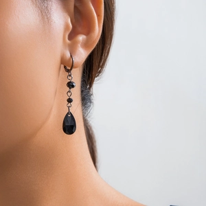 Close-up of black teardrop crystal fringe earrings worn by a model in a gothic style