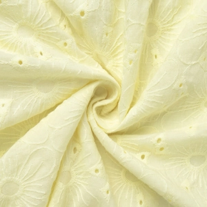 Close-up of yellow cotton dress fabric featuring intricate sunflower broderie anglaise embroidery