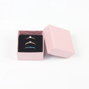 Detailed view of three gold rings inside a pink textured jewelry box with black lining
