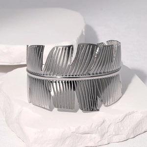 Detail shot of a silver leaf pattern cuff bracelet on a white stone pedestal
