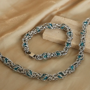 Silver Byzantine style steel necklace and bracelet set with blue beads on silk background