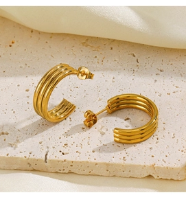 Detailed macro view of gold-plated C-shaped earrings with parallel groove design
