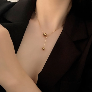 Golden double bead titanium necklace on woman neck wearing a black office blazer
