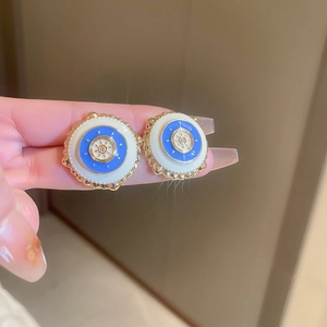 Vue macro de boucles d'oreilles rétro en émail bleu et blanc avec bordure dorée