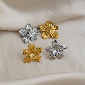 Macro view of gold and silver trumpet flower stud earrings with delicate pleated texture