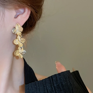Detail of elegant gold floral earrings with textured petals worn by a model